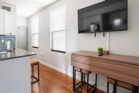 Entryway with room darkening wooden shades, dining seating at kitchen island.
50in Vizio 4K UHD LED smart tv with bar like dining seating that expands to seat 4 people.